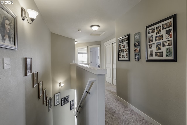 hall with carpet floors, baseboards, and an upstairs landing