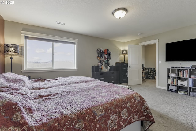 carpeted bedroom with visible vents, a textured ceiling, and baseboards