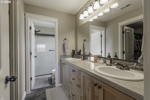 bathroom featuring visible vents, a sink, toilet, and double vanity