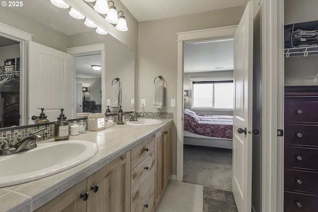 bathroom with double vanity, backsplash, a sink, and ensuite bathroom