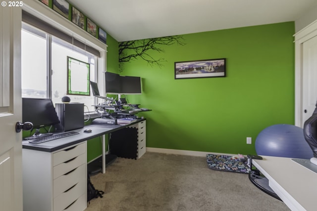 carpeted home office featuring an accent wall and baseboards