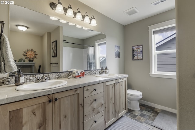 bathroom with toilet, baseboards, a sink, and decorative backsplash