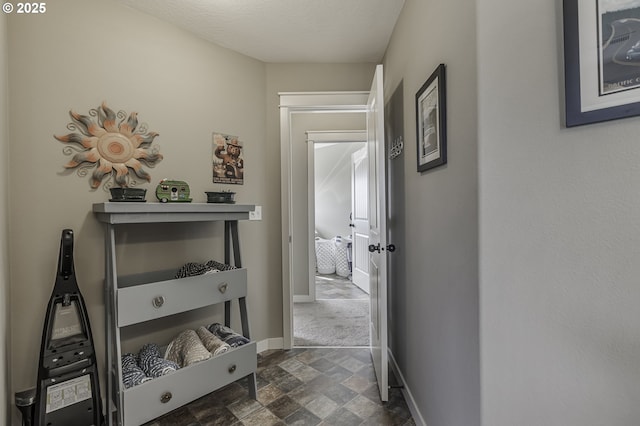 corridor featuring stone finish floor and baseboards