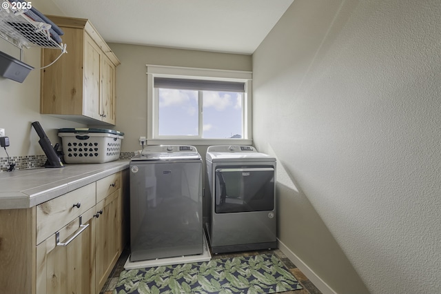 clothes washing area with cabinet space, washer and clothes dryer, and baseboards