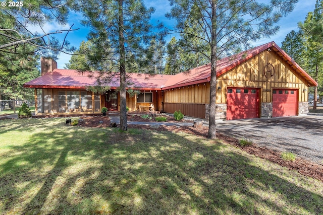 view of front of home featuring a front yard, a chimney, metal roof, and driveway