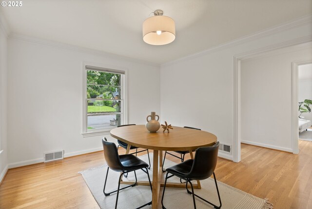 dining room featuring light wood finished floors, ornamental molding, and baseboards