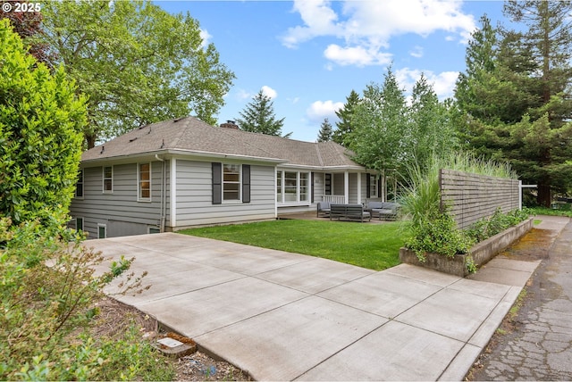 back of house with a yard, a patio, roof with shingles, and an outdoor living space