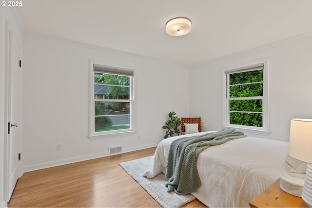 bedroom featuring light wood finished floors, baseboards, and crown molding