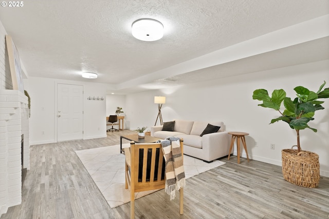 living room featuring light wood-style floors, a textured ceiling, and baseboards
