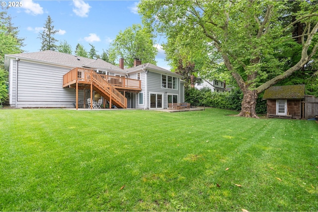 rear view of house with a wooden deck, stairs, an outdoor structure, a chimney, and a yard