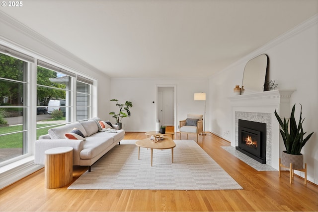 living area with healthy amount of natural light, a fireplace, ornamental molding, light wood finished floors, and baseboards