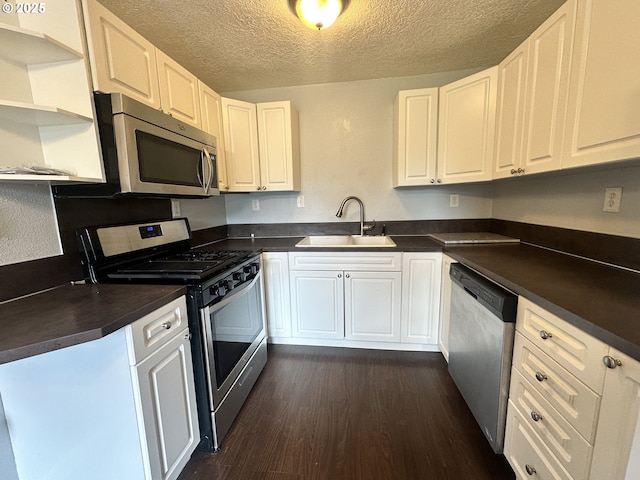kitchen featuring open shelves, dark countertops, stainless steel appliances, and a sink