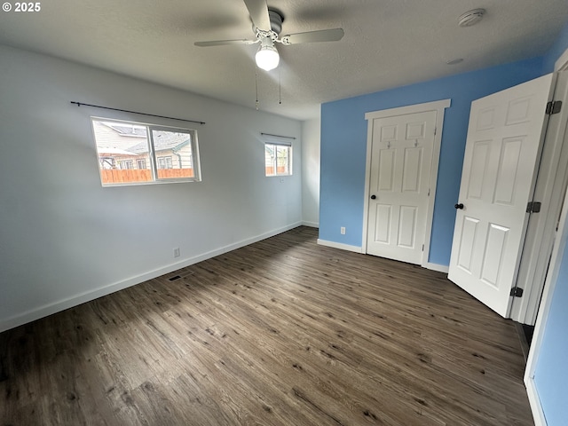 unfurnished bedroom featuring dark wood-type flooring, a textured ceiling, a ceiling fan, and baseboards