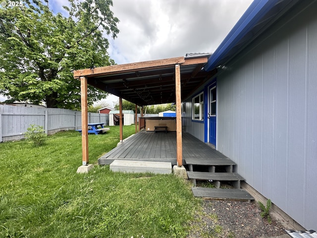 deck featuring a lawn, a fenced backyard, and a hot tub
