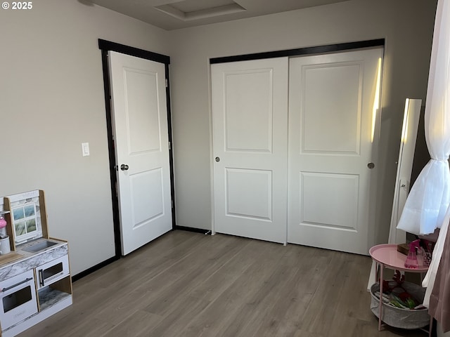 bedroom with attic access, a closet, baseboards, and wood finished floors