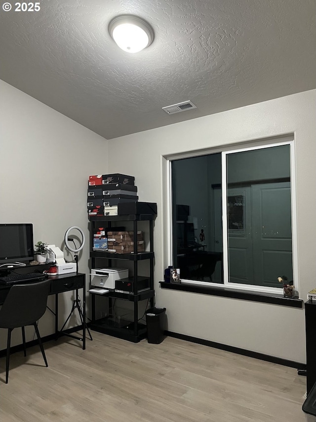 office area featuring visible vents, a textured ceiling, baseboards, and wood finished floors