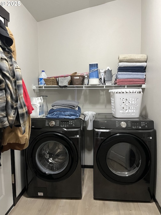 laundry area with laundry area, washer and dryer, and wood finished floors