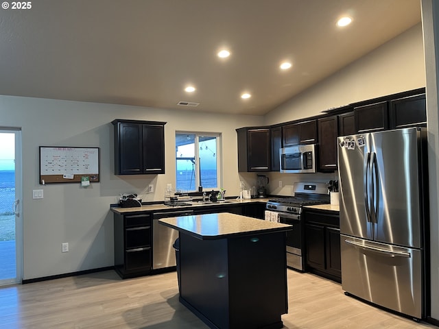 kitchen featuring lofted ceiling, light wood-style floors, a kitchen island, and stainless steel appliances