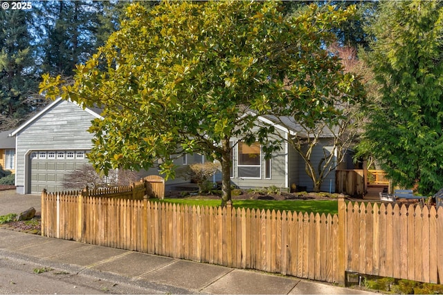 view of property hidden behind natural elements with an attached garage, driveway, and a fenced front yard