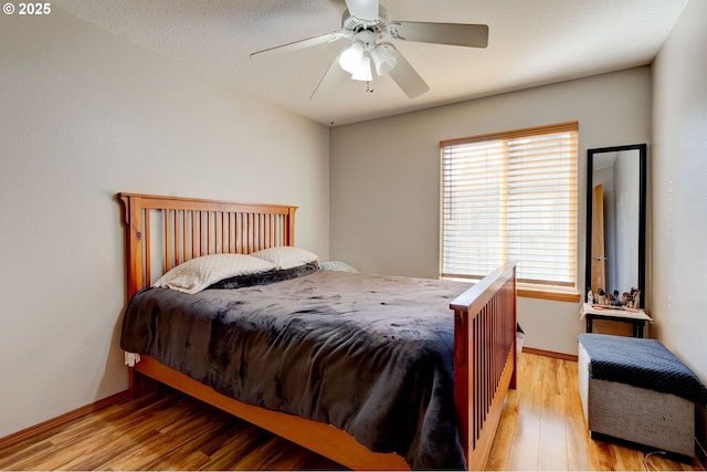 bedroom featuring light wood finished floors, baseboards, and a ceiling fan