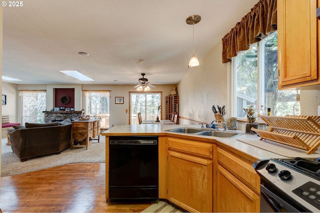 kitchen featuring black dishwasher, open floor plan, a sink, a peninsula, and stainless steel gas range oven