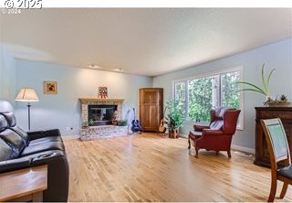 living area with a brick fireplace, wood finished floors, and baseboards