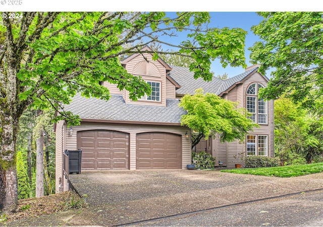 view of front facade with a garage, driveway, and roof with shingles