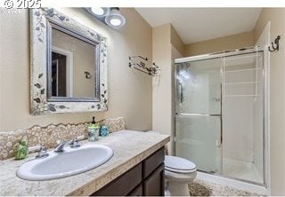 bathroom featuring vanity, toilet, and a stall shower