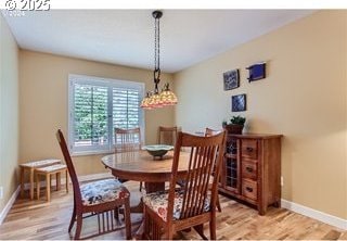 dining space with baseboards and light wood-type flooring