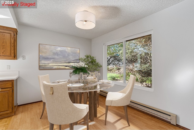 10915 SW Meadowbrook Dr Unit 22, Portland, OR 97224 - dining space with light wood finished floors, a textured ceiling, baseboard heating, and a baseboard heating unit
