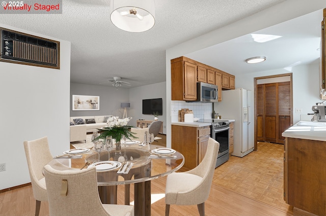 10915 SW Meadowbrook Dr Unit 22, Portland, OR 97224 - dining area with a wall unit AC, ceiling fan, light wood-style floors, and a textured ceiling