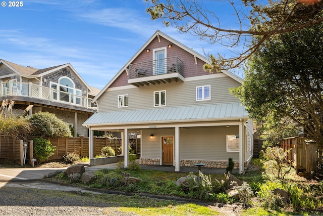 view of front of home featuring a balcony, fence, covered porch, and metal roof