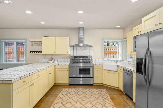 8917 Spindrift Ln, Manzanita, OR 97130 - kitchen with stainless steel appliances, wall chimney exhaust hood, tile counters, a sink, and recessed lighting
