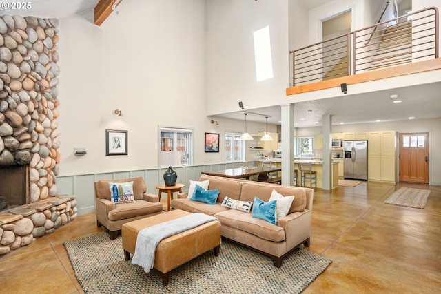 living room featuring a fireplace, a towering ceiling, and a healthy amount of sunlight