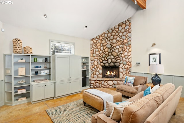 living area featuring a stone fireplace, beamed ceiling, high vaulted ceiling, and a wainscoted wall