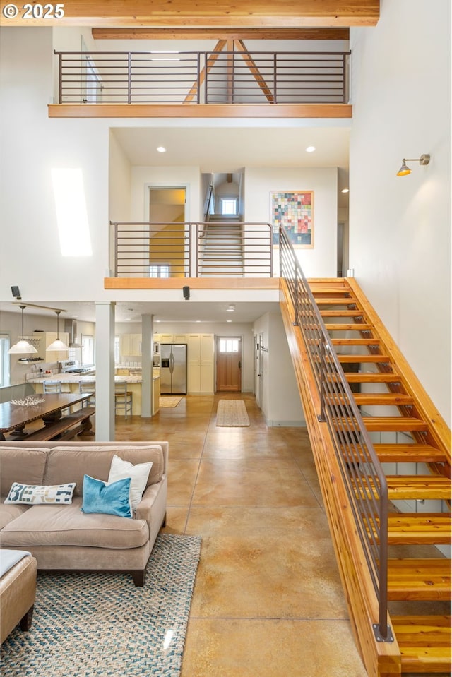 living area with stairway, concrete flooring, and a high ceiling