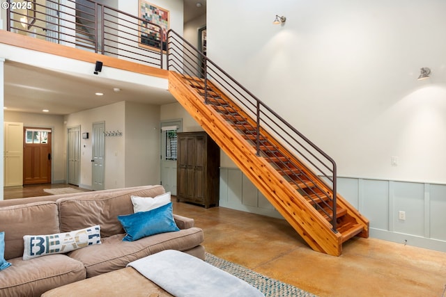 8917 Spindrift Ln, Manzanita, OR 97130 - living area featuring concrete floors, stairs, a high ceiling, a decorative wall, and recessed lighting