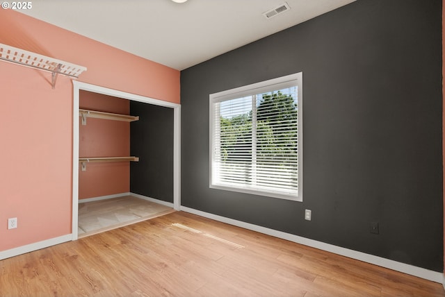 unfurnished bedroom with baseboards, wood finished floors, and a closet