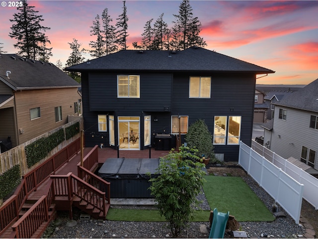 back of property with a hot tub and a deck