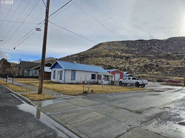 single story home with metal roof, a garage, fence, driveway, and a front lawn