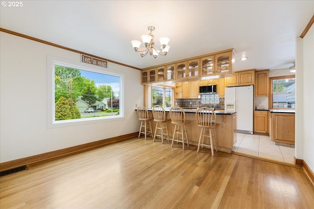 3400 SW 110th Ave, Beaverton, OR 97005 - kitchen featuring glass insert cabinets, white refrigerator with ice dispenser, stainless steel microwave, light wood finished floors, and a notable chandelier
