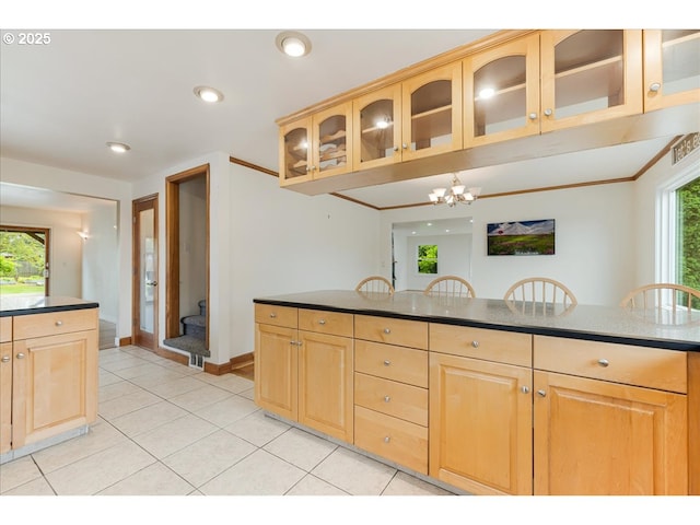 kitchen with light tile patterned floors, light brown cabinetry, glass insert cabinets, and a notable chandelier