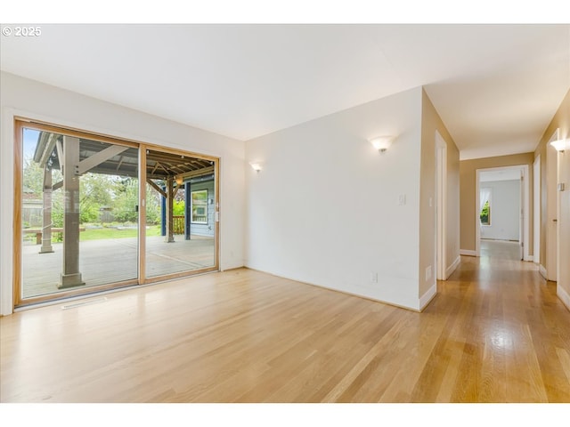 empty room featuring baseboards and light wood finished floors