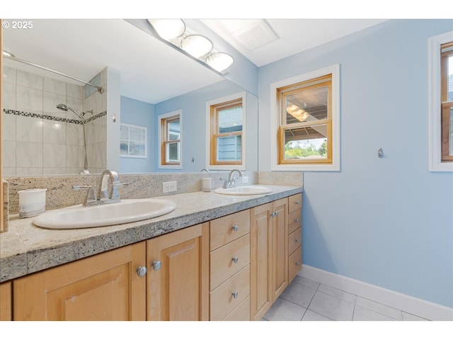 bathroom featuring double vanity, tiled shower, a sink, and tile patterned flooring