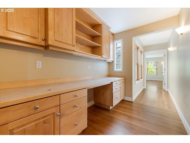 kitchen featuring light countertops, open shelves, built in desk, and wood finished floors