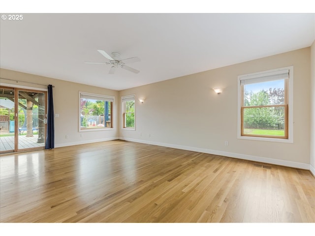 empty room featuring baseboards, plenty of natural light, ceiling fan, and light wood finished floors