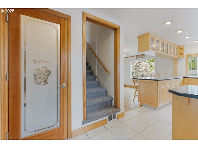 kitchen featuring light brown cabinetry, a kitchen breakfast bar, visible vents, and light tile patterned floors