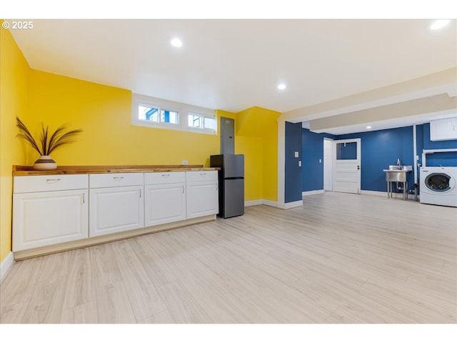 kitchen featuring baseboards, freestanding refrigerator, washer / clothes dryer, and white cabinetry