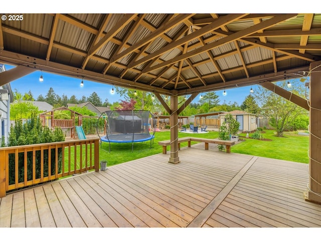 deck with a storage unit, a playground, a lawn, a trampoline, and an outbuilding