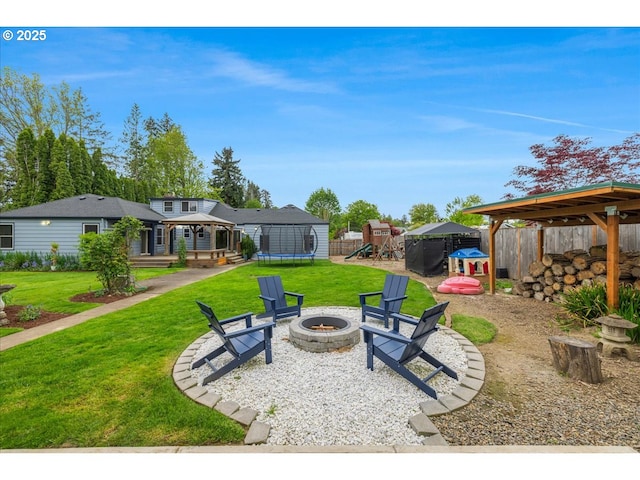 exterior space featuring fence, a trampoline, a gazebo, an outdoor fire pit, and a playground